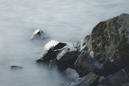 Abstract long exposure of waves and rocks in lake shore at dawnの写真素材