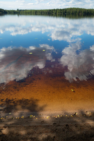 Sky reflecting on lake surface at small beach background