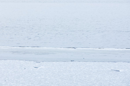 Partially frozen lake surface and snow at winter dayの写真素材