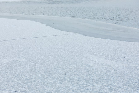 Partially frozen lake surface and snow at winter dayの写真素材