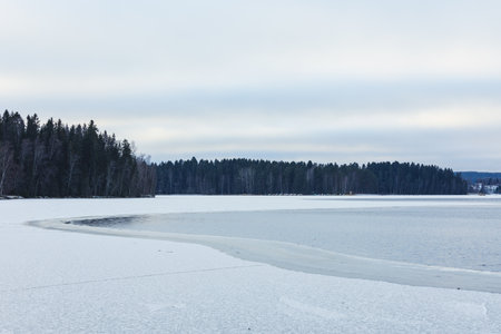 Partially frozen lake surface and snow at winter dayの写真素材