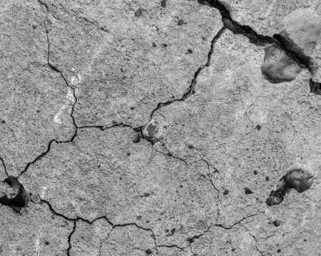 A high resolution old concrete cement with cracks and natural destruction from time and weather conditions. Non-color, monochrome black and white photo.の写真素材