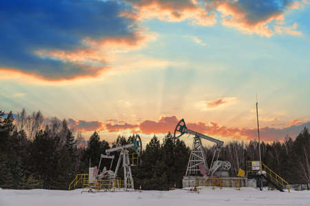 Oil pumps. Russia Oil industry equipment. Oil rig energy industrial machine for petroleum crude. Oil crisis. Fiery red clouds from the glow of the sun. Oil crisis. War on oil prices.の写真素材