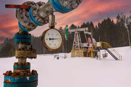 Pipeline Manometer Oil pressure gauge shows 4 MPa. Oil crude usa pump jack winter working. Oil rig energy industrial machine for petroleum in the sunset backgroundの写真素材
