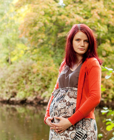 pregnant woman walking in autumn parkの写真素材