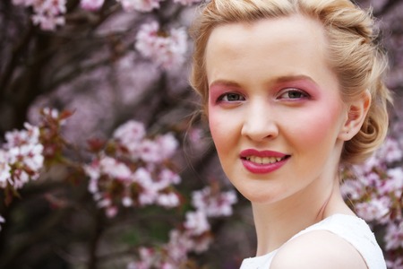 woman smelling flowers in blooming sakura gardenの写真素材