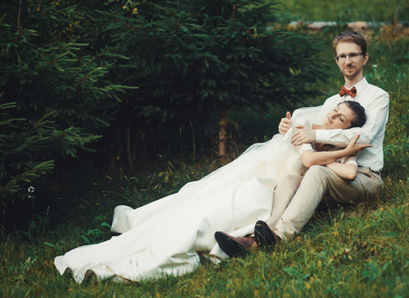 Honeymoon. The bride and groom sitting on grass. Summer time.の写真素材