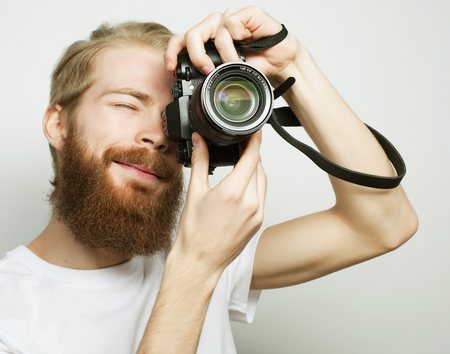 Travel, technology and life style concept: young bearded  photographer taking pictures with digital camera.の写真素材