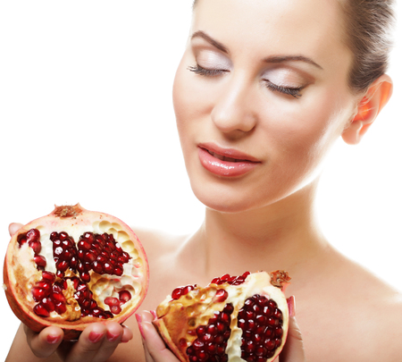 Portrait of a beautiful young woman with a pomegranate. Isolated on white.の写真素材