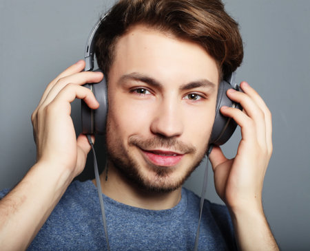 Handsome young man wearing headphones and listening to music. Emotion concept.