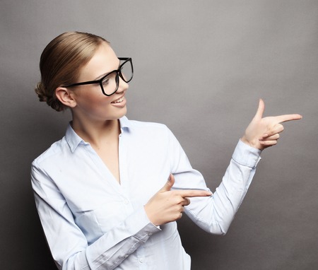 Happy smiling young beautiful business woman showing something or copyspase for product or sign text,  over grey backgroundの写真素材