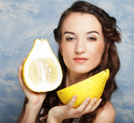 Girl holds big citrus fruit - pamelo, over sky background