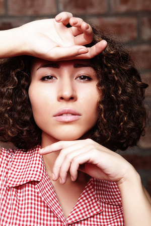 attractive curly woman on brick wallの写真素材