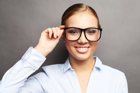 happy smiling young business woman in glasses, over grey  backgrの写真素材