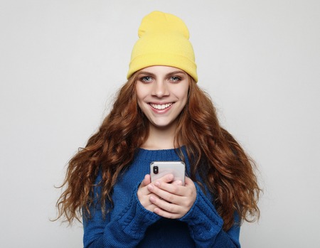 lifestyle, emotional and people concept: Young curly woman with smart phoneの写真素材