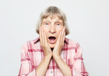 lifestyle, emotion and people concept: Aged grandmother with shocked face. Portrait of grandmother with pink shirt.の写真素材