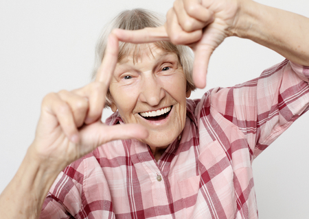 lifestyle, emotion and people concept: Aged grandmother with shocked face. Portrait of grandmother with pink shirt.の写真素材