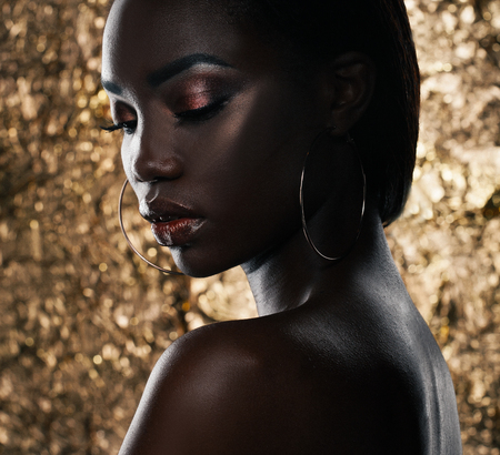 Fashion studio portrait of an extraordinary beautiful african american model with closed eyes  over golden backgroundの写真素材