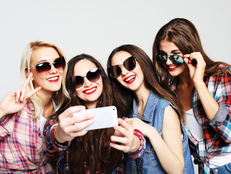 happy teenage girls with smartphone taking selfieの写真素材