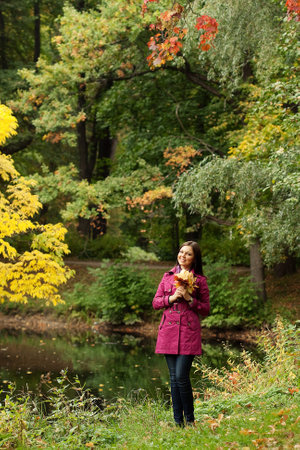 Young woman with autumn leaves in parkの写真素材
