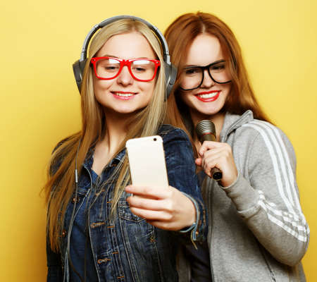 two girls with a microphone singing and having fun together, make selfieの写真素材