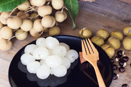 longans on a black plate and a wood fork on a wood  tableの写真素材