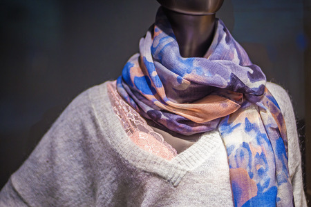 Mannequin with a patterned scarf and a warm woolen sweater on a dark backgroundの写真素材