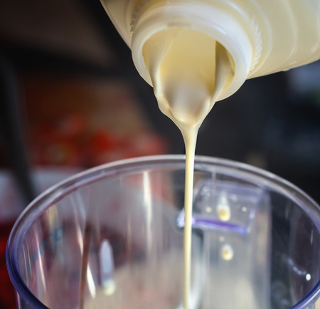 The cream is poured from a plastic bottle into a bowl. Close up., pouredの写真素材