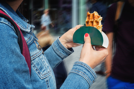 Traditional belgian wafle in woman's hands on a streetの写真素材