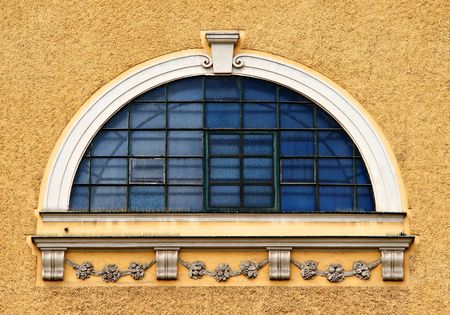 round blue window with bars on light brown facadeの写真素材