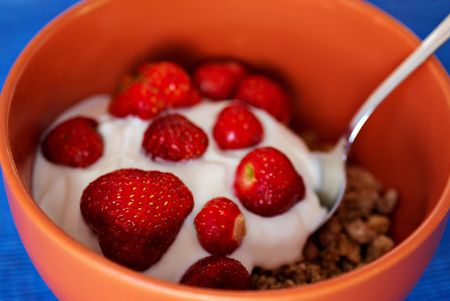 Cereals with yogurt and strawberries and metal spoon, shallow deep of field, blue backgroundの写真素材