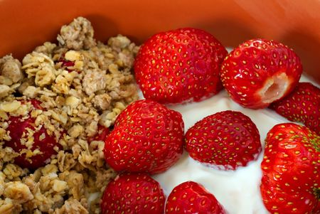 Cereals with strawberry and yogurt in orange bowlの写真素材