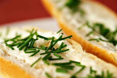 Close up detail of bread roll with cheese and chives, shallow DOF, red - purple background, white plate,の写真素材