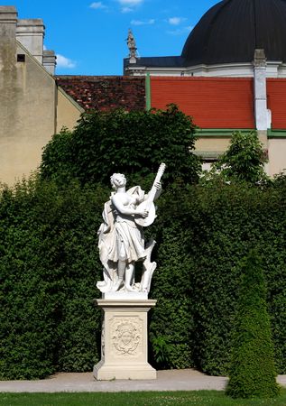 Statue of women playing guitar in a gardenの写真素材