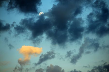 Moon and clouds in sunrise, one of clouds illuminated by rising Sunの写真素材