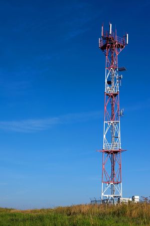 Telecommunication tower on a meadow in sunny day with blue skyの写真素材