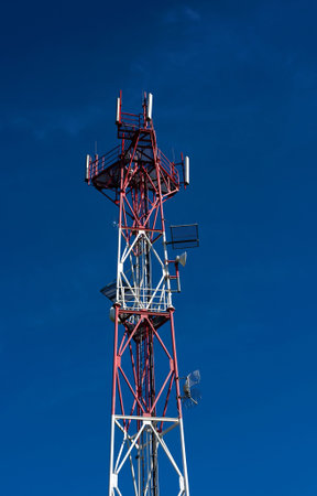 detail of red white telecommunication tower on blue sky