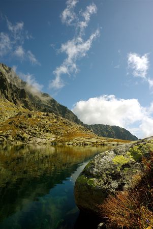 Mountain lake and a boulder with blue sky with some cloudsの写真素材