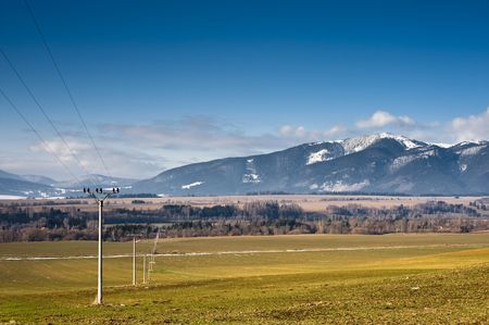 electric poles on filds in sunny day with mountainsの写真素材