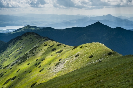 Mountain ridge in summer with cloudy sky and a lake in backgroundの写真素材
