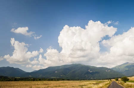 Summer fields with mountains and clouds in backgroundの写真素材