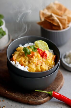 Hot spicy lentil curry in bowl. Vegetable curry with rice, indian naan butter bread pita, spices, lime and herbs. Traditional Indian British dish, popular indian curry. Asian food cuisine. Close-upの写真素材
