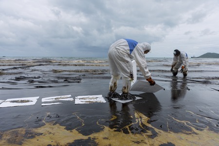 RAYONG, THAILAND - JULY 31, 2013: Workers remove and clean up crude oil spilled with absorbent paper from Prao Bay on July 31, 2013 in Samet Island, Rayong, Thailandのeditorial素材
