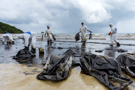 RAYONG, THAILAND - JULY 31, 2013: Workers remove and clean up crude oil spilled with absorbent paper from Prao Bay on July 31, 2013 in Samet Island, Rayong, Thailandのeditorial素材