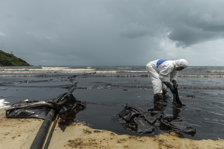 RAYONG, THAILAND - JULY 31, 2013: Workers remove and clean up crude oil spilled with absorbent paper from Prao Bay on July 31, 2013 in Samet Island, Rayong, Thailandのeditorial素材