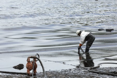 RAYONG, THAILAND - JULY 31, 2013: A worker in biohazard suit during the clean-up operation from crude oil spilled into Ao Prao Beach on July 31, 2013 in Rayong province, Thailand.のeditorial素材