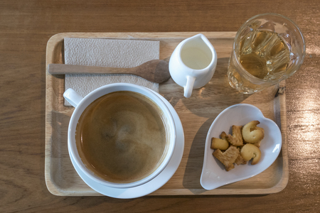 Coffee time in morning set hot americano with milk tea and cracker in wooden tray on wood table, top viewの写真素材