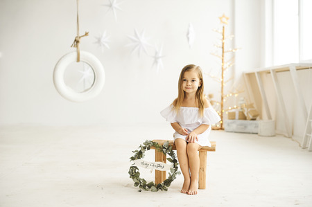 A beautiful little girl playing with a swing boat in the white roomの写真素材