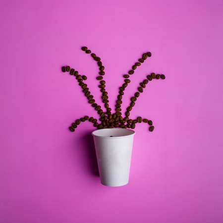 Top view of coffee beans form a hot steam on an empty white disposable cup on a pink background.の写真素材