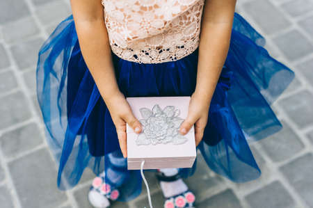 Close up top view of a wooden pink box with a flower in the hands of a little girl.の写真素材
